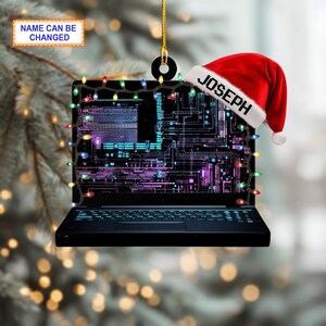 May include: A black laptop Christmas ornament with a Santa hat that says "JOSEPH". The laptop screen displays a circuit board design and is decorated with colorful string lights. The text "NAME CAN BE CHANGED" is also visible.