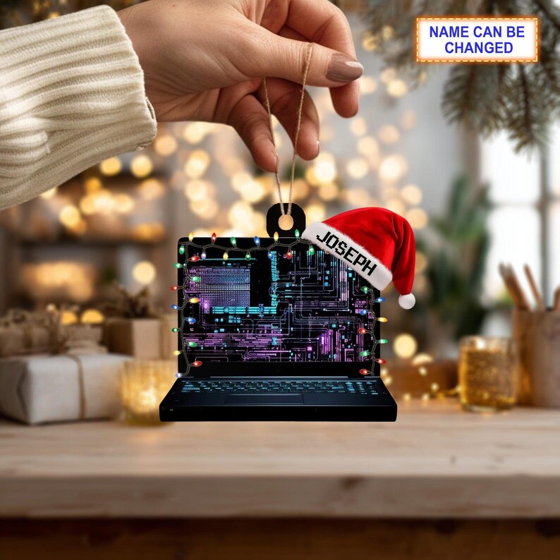 May include: A black laptop-shaped Christmas ornament with a red Santa hat that says "JOSEPH". The ornament is decorated with colorful lights and a circuit board design. The text "NAME CAN BE CHANGED" is also visible.