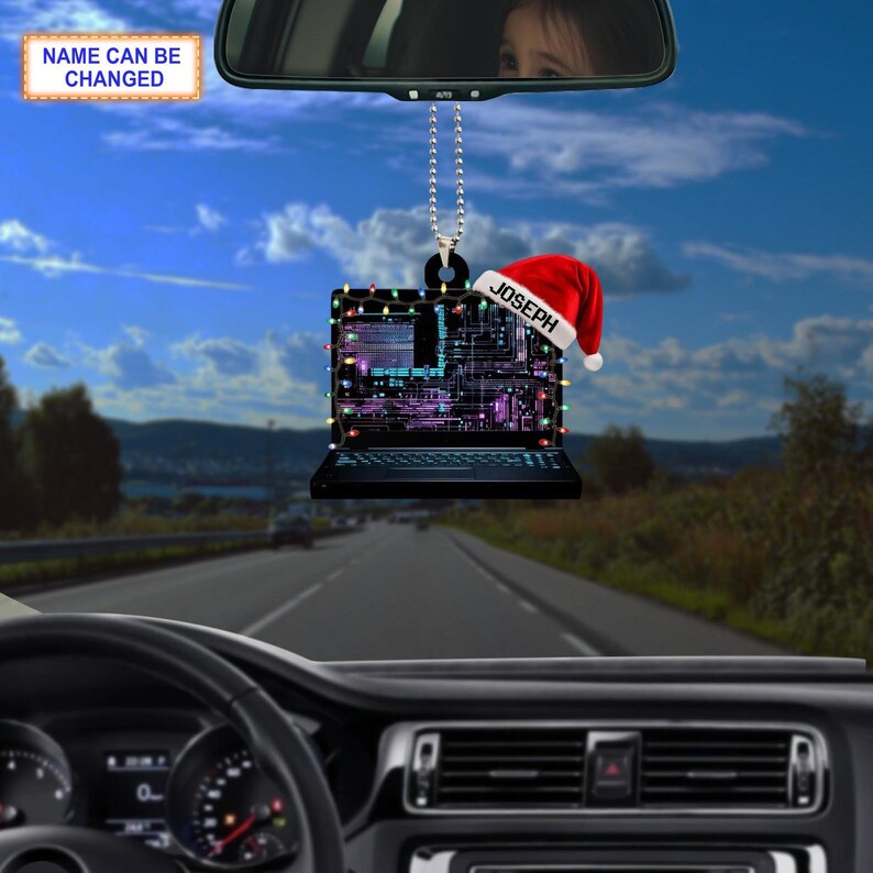 May include: A black laptop-shaped car ornament with a festive Christmas theme. The laptop is decorated with colorful lights and a Santa hat with the name "JOSEPH". The ornament hangs from a silver chain, with the text "NAME CAN BE CHANGED" on a sign.