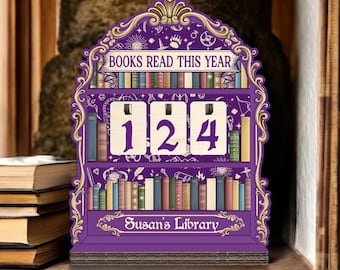 May include: A purple wooden bookshelf-shaped counter with the text "BOOKS READ THIS YEAR" and the number "124". The bottom of the counter reads "Susan's Library". The bookshelf is decorated with gold accents and illustrations of books.