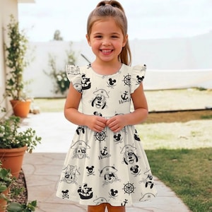 May include: A cream-colored dress with a pirate-themed print featuring cartoon characters, anchors, and ship wheels. The dress has short, ruffled sleeves and a round neckline. The word "Hooked" is printed on the dress.