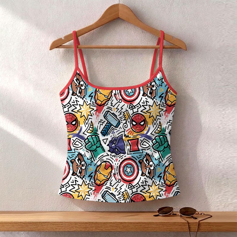 K&ouml;nnte beinhalten: Ein wei&szlig;es Camisole mit roter Bord&uuml;re und Tr&auml;gern, mit einem farbenfrohen Muster aus Comicfiguren und Symbolen. Das Design umfasst Bilder von Spider-Man, Captain America und Thor.