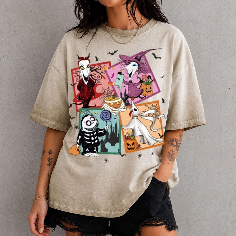 Może przedstawiać: Beżowy t-shirt z kr&oacute;tkim rękawem z nadrukiem graficznym składającym się z czterech kwadratowych paneli przedstawiających postacie z Miasteczka Halloween, w tym Locka, Shocka, Barrela i Zero, w otoczeniu małych nietoperzy i pajęczyn.