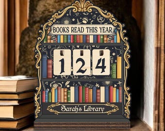 May include: A wooden bookshelf-shaped counter with the text "BOOKS READ THIS YEAR" and "124" displayed. The counter has a black background with gold accents and a decorative frame. The bottom of the counter reads "Sarah's Library".