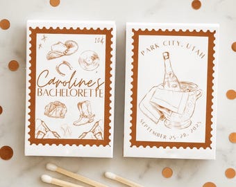 May include: Two matchboxes with brown borders and white centers. One box says "Carolines BACHELORETTE" with cowboy-themed illustrations. The other says "PARK CITY, UTAH" with a champagne bottle in a bucket. Matches are in the foreground.