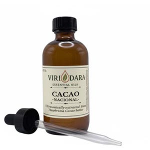 May include: A brown glass bottle of essential oil with a black cap and a dropper. The label reads "Viri Dara Essential Oils Cacao - Nacional". The dropper is lying next to the bottle. The oil is ultrasonically extracted from Theobroma Cacao butter.