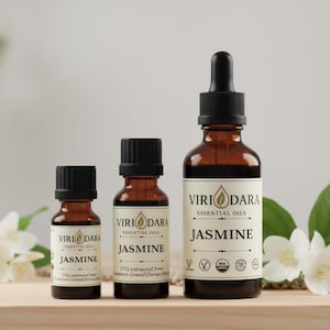May include: Three amber glass bottles of jasmine essential oil, labeled "Viri Dara Essential Oils." The bottles vary in size, with black caps and white labels. The labels read "Jasmine" and include the text "CO2 extracted from Jasminum Grandiflorum Flowers."