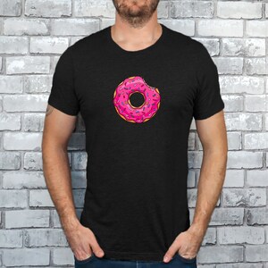 May include: A black t-shirt with a pink donut with sprinkles and a bite taken out of it.