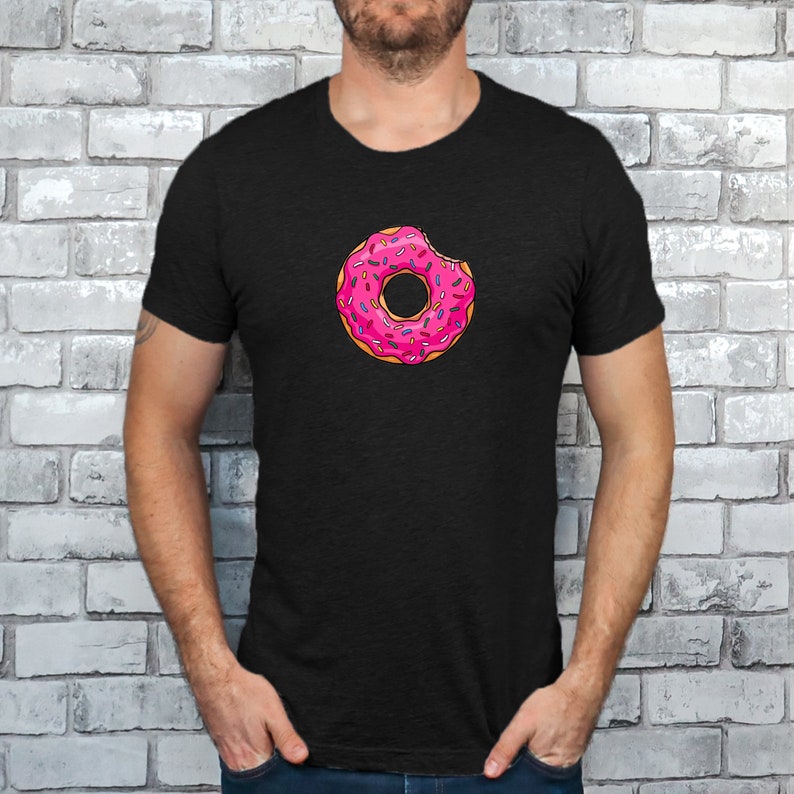 May include: A black t-shirt with a pink donut with sprinkles and a bite taken out of it.