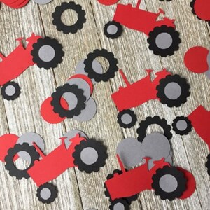 May include: Red and gray paper cutouts of tractors with wheels. The tractor cutouts are scattered on a woodgrain surface.