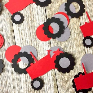 May include: Red and black paper cutouts of tractors with gray wheels. The cutouts are scattered on a wooden surface.