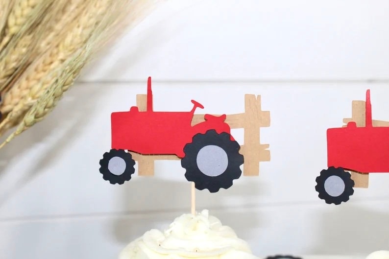 K&ouml;nnte beinhalten: Rote Traktor-Cupcake-Topper mit schwarzen R&auml;dern und einem hellbraunen Zaun-Design. Diese Dekorationen zum Thema Bauernhof sind perfekt f&uuml;r eine Geburtstagsfeier oder ein anderes besonderes Ereignis. Die Topper sind an Holzst&auml;ben befestigt.