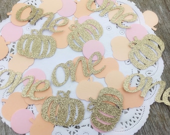 Può includere: Confetti dorati glitter con la parola "one" e forme di zucca in colori pesca e rosa.