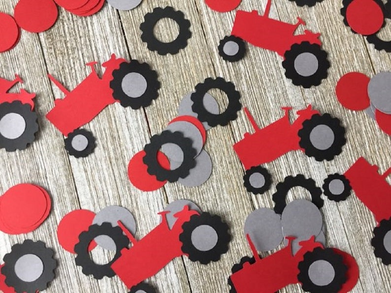 May include: Red and black paper tractor cutouts with gray circles. These are party decorations for a farm-themed party.