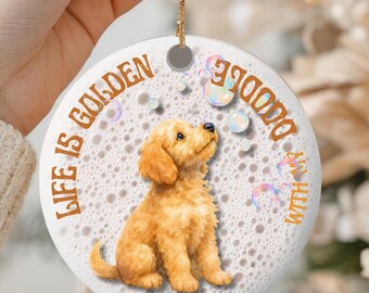 May include: A round white ceramic ornament featuring a golden-colored puppy sitting in the center. The text "LIFE IS GOLDEN" is printed in brown letters on the left, and "WITH MY DOODLE" is on the right. The background has a bubble pattern.