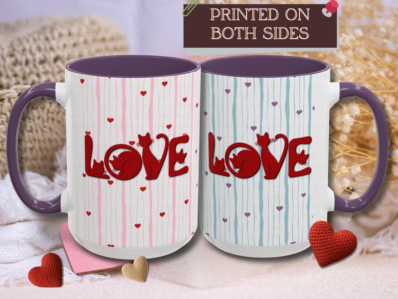 May include: Two white ceramic mugs with purple handles and interiors. Each mug features the word "LOVE" in red, with a cat silhouette replacing the "O". The mugs have vertical striped patterns in pink and blue, with small heart accents. The text "PRINTED ON BOTH SIDES" is at the top.