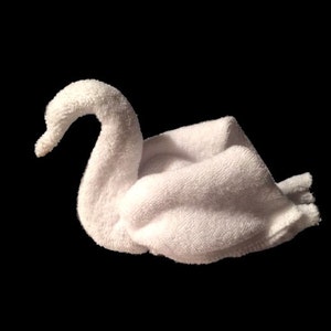 May include: A white towel folded into the shape of a swan. The swan is facing the right side of the image.