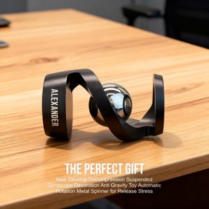 May include: A black metal desktop spinner with a silver ball in the center. The word "ALEXANDER" is printed on the side. The text "THE PERFECT GIFT" is below the spinner.