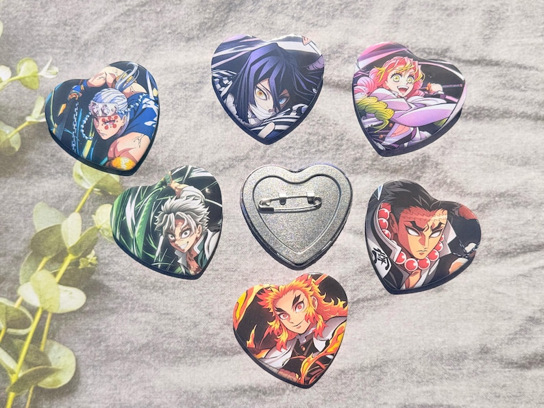 May include: A collection of heart-shaped pinback buttons featuring colorful anime character illustrations. The buttons showcase various characters with detailed artwork and vibrant colors, perfect for fans of the series.