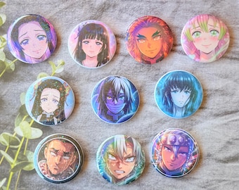 May include: A collection of ten circular pin-back buttons featuring colorful anime-style character illustrations. Each button displays a unique portrait with distinct facial expressions, hair colors, and vibrant artistic details set against varied backgrounds.