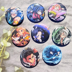 Può includere: Una collezione di sette bottoni rotondi con personaggi anime. Ogni bottone presenta un personaggio diverso con colori vivaci e opere d'arte dettagliate. I bottoni sono disposti su una superficie grigio chiaro, mostrando la varietà dei design.