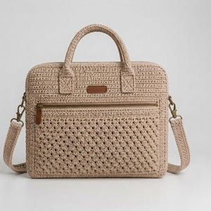 May include: A beige crochet laptop bag featuring a rectangular silhouette, two top handles, and a detachable shoulder strap. The front includes a horizontal zippered pocket with a brown leather-like rectangular patch centered above the zipper.