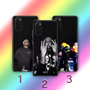 May include: Three black phone cases with images of musicians. The first case features a person in a black sweatshirt and white hat. The second case displays a person in a bandana making hand gestures. The third case shows a person on stage with flames.