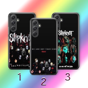 Puede incluir: Tres fundas negras para teléfono con diseños de Slipknot. Cada funda presenta un diseño diferente, incluyendo el logotipo de la banda e imágenes de los miembros. El texto "WE ARE NOT YOUR KIND" también es visible en dos de las fundas.