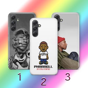 May include: Three phone cases with different designs. One case is black and white with a portrait. Another is white with a cartoon figure and the text "PHARRELL IN MY MIND". The third case is silver with a person wearing a red hat.