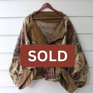 May include: A vintage jacket with a floral pattern in shades of green, red, and beige. The jacket features a corduroy collar and trim, and the word "SOLD" is displayed on a brown rectangle.