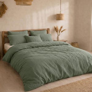 Pode incluir: Uma cama com estrutura de madeira e roupa de cama verde sálvia. O conjunto inclui uma capa de edredão e várias almofadas. O quarto tem uma paleta de cores neutras com texturas naturais, incluindo um tapete tecido e luminárias suspensas.