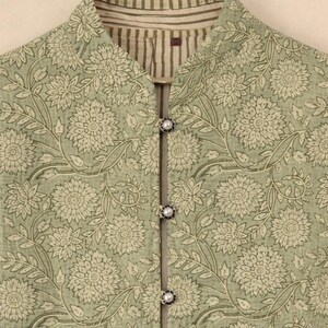 May include: A light green floral print jacket with a mandarin collar and three pearl-like buttons. The jacket features a repeating pattern of large flowers and leaves in a muted color palette. The collar has a striped lining.