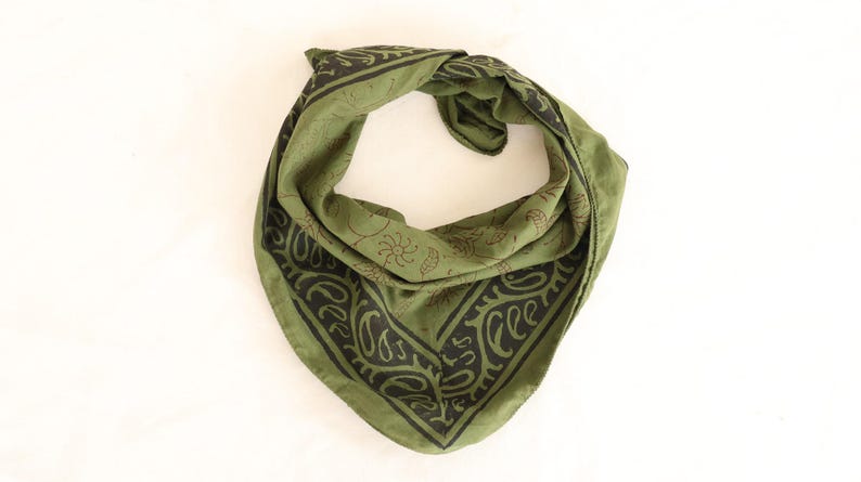 May include: A triangular olive green bandana featuring a dark brown border with a repeating paisley pattern and a central section decorated with small, delicate line-drawn botanical motifs including leaves, stems, and sun-like circular shapes.