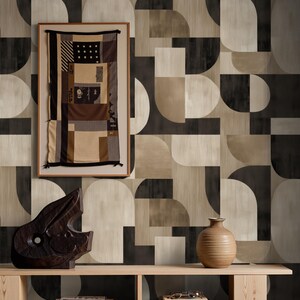 May include: A wooden console table against a geometric wallpaper. It features a dark wooden sculpture, a framed textile artwork, and a ceramic vase. Books and spectacles are also visible on the table.