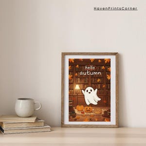 Könnte beinhalten: Ein gerahmter Druck mit Holzrahmen zeigt eine skurrile Herbstszene. Das Kunstwerk zeigt einen freundlichen Geist, Kürbisse und den Text "hello autumn" vor dem Hintergrund einer Bibliothek mit Herbstblättern.
