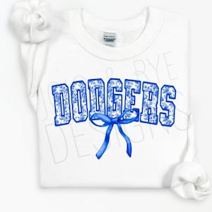 Puede incluir: Sudadera blanca con la palabra "DODGERS" en letras azules con estampado floral y un lazo azul. La sudadera tiene cuello redondo y mangas largas. Las mangas est&aacute;n enrolladas.