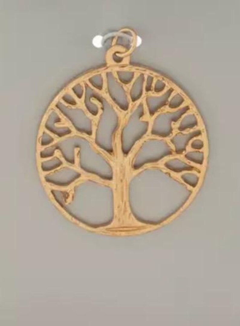 May include: Gold-coloured pendant with a tree of life design. The circular pendant has an openwork pattern showing the tree's branches and roots. It has a small loop at the top for a chain or cord.