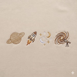 May include: Embroidered space design with Saturn, a rocket with flames, crescent moons, stars, a galaxy, and a telescope. The embroidery is in brown, gold, and white on a beige background.