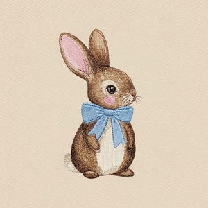 May include: Embroidered image of a brown bunny with pink inner ears and a light blue bow tie. The bunny has a white belly and a pink cheek. The background is a light beige color. The image is a close-up of the bunny.