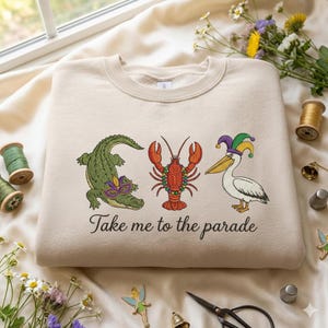 Broderad design med "Ta mig till paraden", broderad design med "Mardi Gras"-alligator, pelikan, kräftor, design med "Fettisdagen".