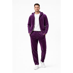 Puede incluir: Un chándal de terciopelo morado oscuro que consta de una sudadera con capucha y cremallera de manga larga con cordón y pantalones rectos a juego con cintura elástica y cordón, sobre una camiseta blanca de cuello redondo y zapatillas.