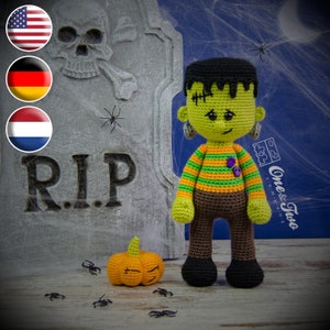 May include: A green crocheted Frankenstein monster doll with black hair, green and orange striped shirt, brown pants, and black shoes. The doll is standing in front of a tombstone with the inscription "RIP". A small orange crocheted pumpkin is in the foreground.