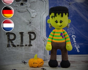 May include: A green crocheted Frankenstein monster doll with black hair, green and orange striped shirt, brown pants, and black shoes. The doll is standing in front of a tombstone with the inscription "RIP". A small orange crocheted pumpkin is in the foreground.
