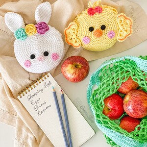 May include: Two round crochet pouches, one white rabbit with colorful flowers and one yellow chick with a red bow. A spiral-bound notepad with the handwritten text Shopping List, Eggs, Onions, Lemons, two colored pencils, a red apple, and a green net bag.