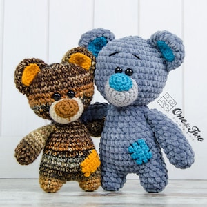 Puede incluir: Dos osos de peluche tejidos a crochet, uno marrón con detalles naranjas y otro azul con detalles turquesa. Los osos están de pie uno al lado del otro y parecen ser amigos.