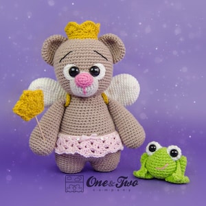 Könnte beinhalten: Ein gehäkelter brauner Bär, der ein rosa Tutu und eine goldene Krone trägt und einen goldenen Sternstab hält. Der Bär hat große schwarze Augen und eine rosa Nase. Ein grüner gehäkelter Frosch sitzt neben dem Bären. Das Bild ist vor einem violetten Hintergrund.