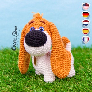 May include: Crocheted stuffed dog toy with brown and white fur, blue eyes, and a black nose. The dog is wearing a gold collar.