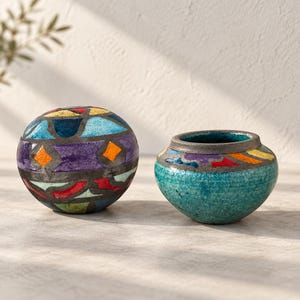 May include: A spherical ceramic object and a small bowl with a crackled turquoise glaze. The sphere features a mosaic-like pattern of blue, purple, red, yellow, and orange shapes separated by dark lines. The bowl has a matching colorful rim.