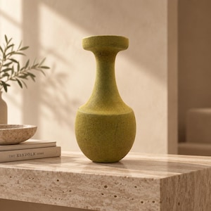 May include: A tall, bulbous vase with a textured, matte chartreuse green finish. The vessel features a narrow, elongated neck that flares slightly at the top opening, creating a distinct silhouette with a rounded base and a flat, circular rim.