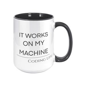 Może przedstawiać: Biały ceramiczny kubek z czarnym wnętrzem, uchwytem i obramowaniem. Kubek zawiera napis "IT WORKS ON MY MACHINE" z napisem "CODING LIFE" poniżej. Idealny prezent dla programistów i koderów.